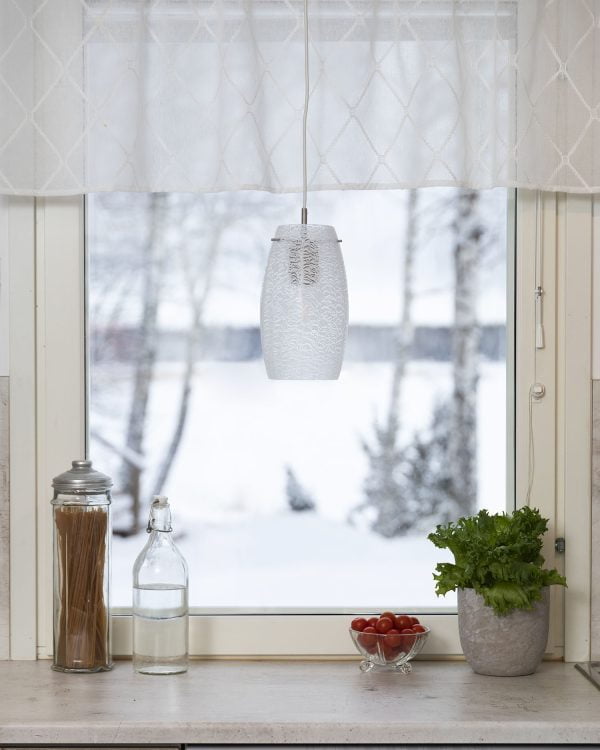 Valkoinen valaisin ikkunalla. Taustalla on luminen maisema.