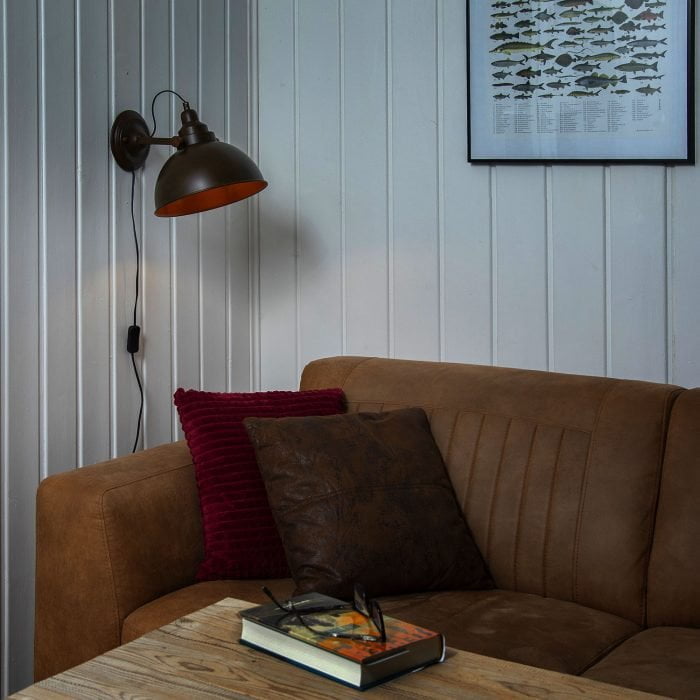 Tumman ruskea seinävalaisin valkoisessa olohuoneessa sohvan vieressä
