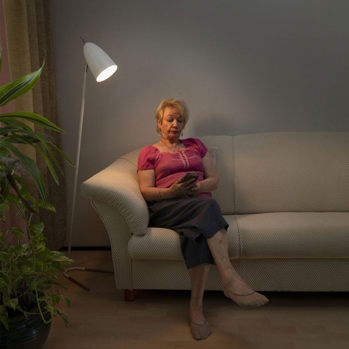 Valkoinen lattiavalaisin sohvan vieressä lukuvalona.