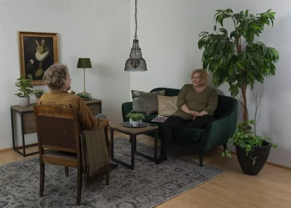 Olohuoneen sisustus jossa Aileen kattovalaisin, Nicole pöytävalaisin, Pavia varjostin sekä kaksi henkilöä keskustelemassa.