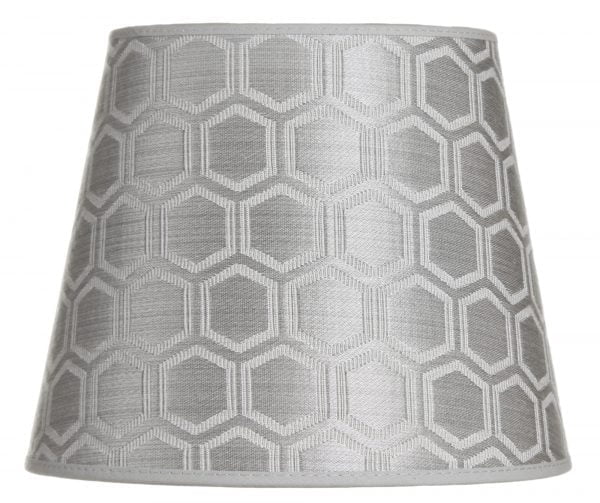 Lampunvarjostin jossa on geometrinen kuvio. Varjostin on materiaaliltaan laminoitua kangasta ja sen väri on hopea.