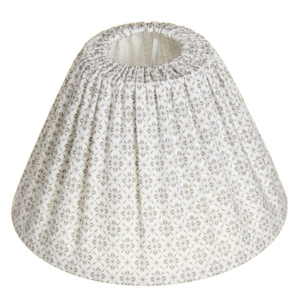 Lampunvarjostin jossa on valkoisella pohjalla beige kukkakuvio. Varjostin on materiaaliltaan kangasta.