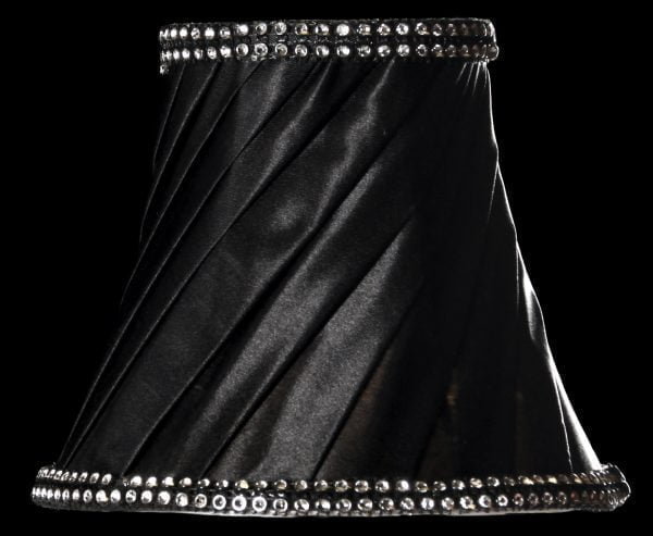 Kruunuvarjostin jonka materiaalina on vuoritettu kangas. Varjostimen väri on musta ja molemmissa reunoissa on strassi koriste.