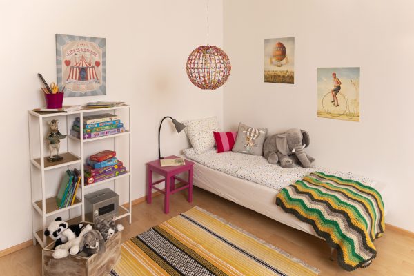 Lastenhuoneen sisustus, jossa on värikäs kattovalaisin ja harmaa lukuvalo.