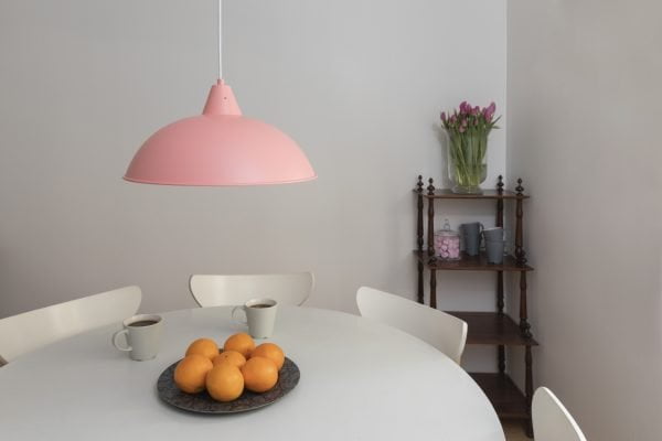 Keittiön sisustus, jossa on metallinen pinkki Lulu kattovalaisin pyöreän valkoisen pöydän päällä sekä ruskea hyllly.