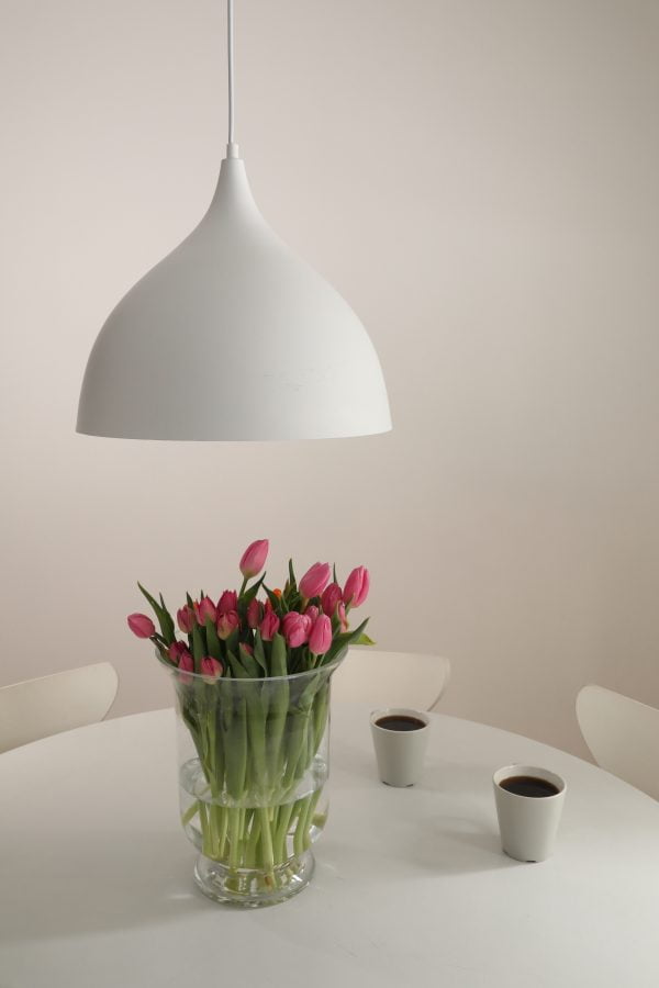 Keittiön sisustus jossa pöydän päällä on valkoinenLuvia kattovalaisin ja pöydällä kaksi kahvikuppia ja kukkia maljakossa.