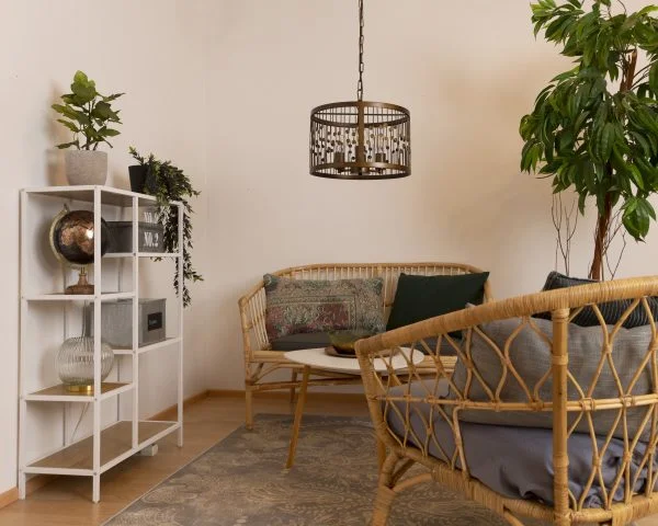 Olohuoneen boho tyylinen sisustus, jossa metallinen Rachel riippuvalaisin bambu kalusteiden seurassa.