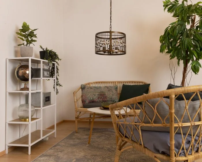 Olohuoneen boho tyylinen sisustus, jossa metallinen Rachel riippuvalaisin bambu kalusteiden seurassa.