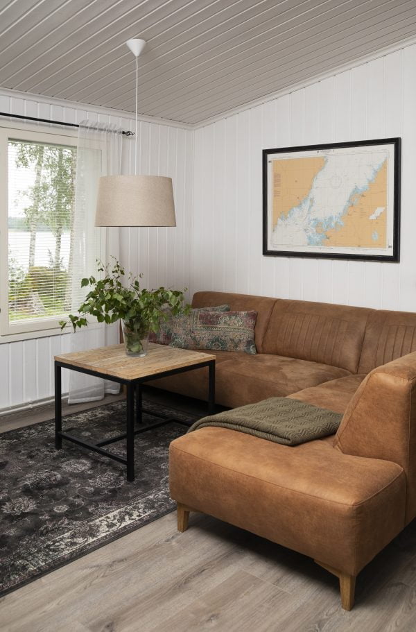 Olohuoneen sisustus jossa on ruskea Pernilla kattovalaisin ruskea sohva ja sohvapöydällä oksia maljakossa.