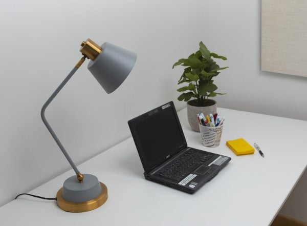Työpöytä, jolla on harmaa Gener-P -pöytävalaisin, läppäri, viherkasvi ja keltaisia lappuja.