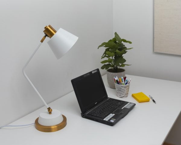 Työpöytä, jolla on valkoinen Gener-P -pöytävalaisin, läppäri, viherkasvi ja keltaisia lappuja.