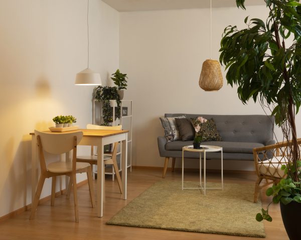 Olohuoneen sisustus, jossa on valkoinen metallinen Carlos riipuvalaisin ruokapöydän päällä sekä bambuvalaisin Lauha sohvapöydän yllä.