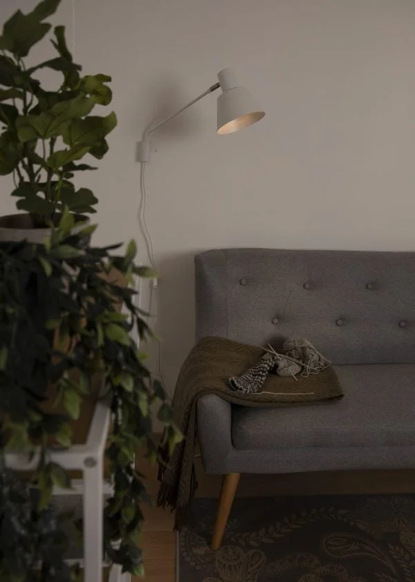 Olohuoneen sisustus, jossa sohvan vieressä käsityövalona on valkoinen Lacus-S seinävalo.