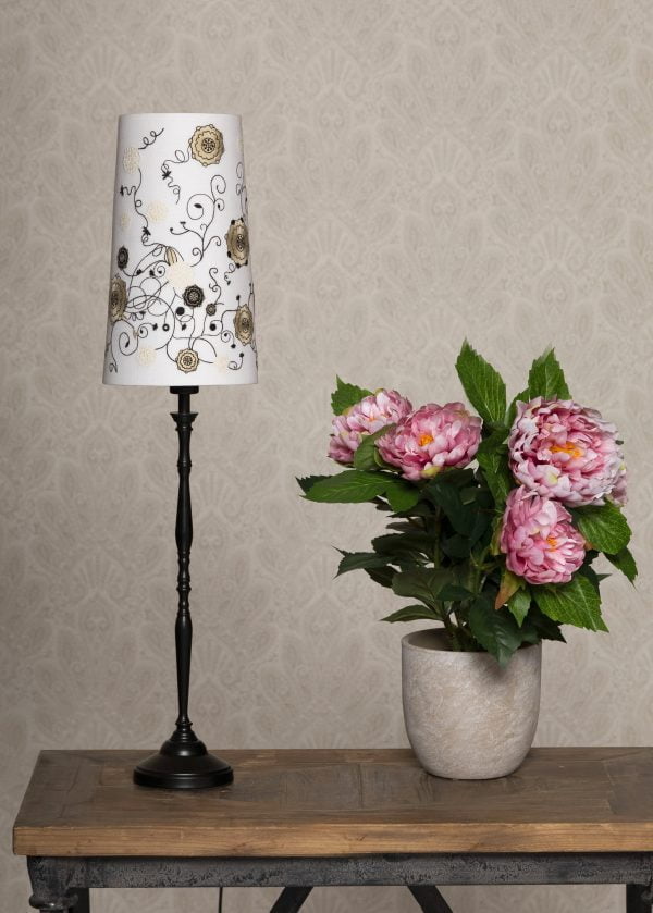 Kirjava lampunvarjostin jonka pääväri on valkoinen. Kukkakuviot on kirjailtu varjostimen pintaan. Valaisimen musta jalka on metallia.