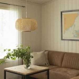Olohuoneen sisustus, jossa Aava bambuvalaisin, ruskea sohva ja sohvapöydällä oksia maljakossa.