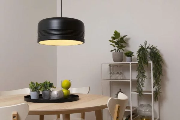Musta riippuvalaisin pyöreän pöydän päällä.