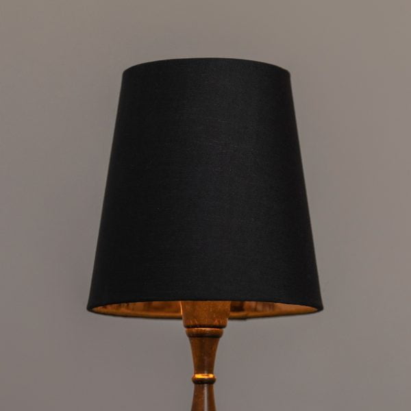 Musta lampunvarjostin, jonka sisäpuoli on kuparin värinen.